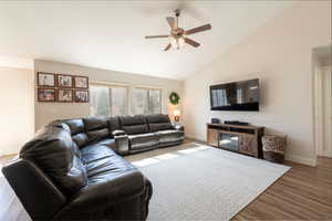 Living area featuring ceiling fan, light wood-style floors, and vaulted ceiling