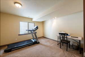 Workout room featuring light carpet and a textured ceiling