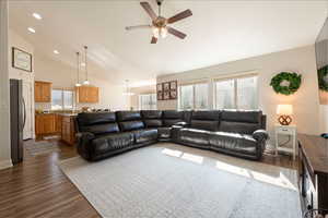 Living room featuring suspended lighting, dark wood-type flooring, a ceiling fan, and vaulted ceiling