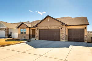 Craftsman inspired home featuring an attached garage, a shingled roof, concrete driveway, and stone siding