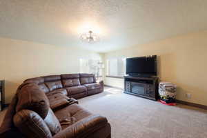 Carpeted living area featuring a textured ceiling and suspended lighting