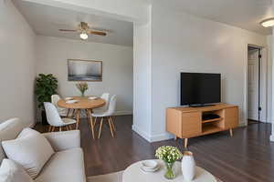 Living area with dark wood finished floors and a ceiling fan