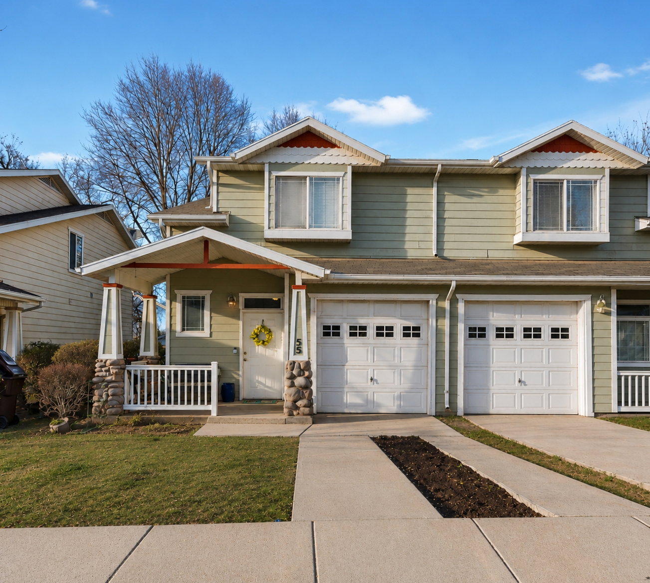 Light green siding exterior with a covered porch featuring stone-clad columns