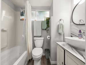 Bathroom featuring vanity, shower / tub combo with curtain, and dark wood-type flooring