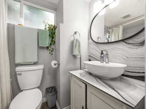 Bathroom featuring a shower with curtain, vanity, and decorative backsplash
