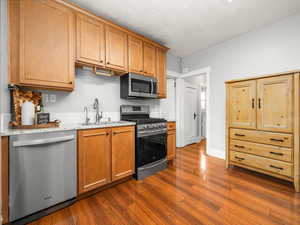 Kitchen with stainless steel appliances, dark wood finished floors, light stone counters, and wood finish cabinets