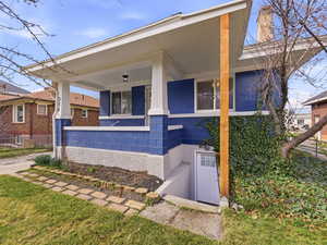 View of front facade with a porch, concrete block siding, and a chimney