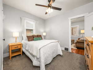 Bedroom with dark carpet and a ceiling fan