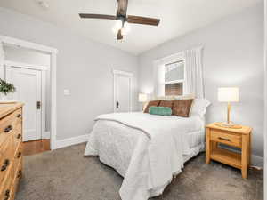 Bedroom with dark carpet, ceiling fan, and a closet