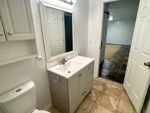Half bathroom with vanity, a textured ceiling, and light stone finish floors