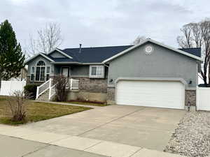 Single story home featuring concrete driveway, a garage, stucco siding, and brick siding
