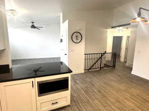 Kitchen featuring a ceiling fan, tiled floors, stainless steel microwave, white cabinets, and open floor plan