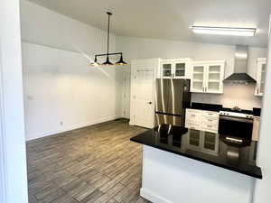 Kitchen with dark countertops, white cabinetry, a peninsula, stainless steel appliances, and finished floors