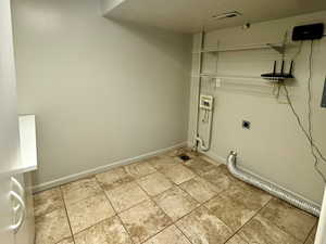 Laundry room with a textured ceiling, electric/gas dryer hookup, light tile patterned flooring, and washer hookup