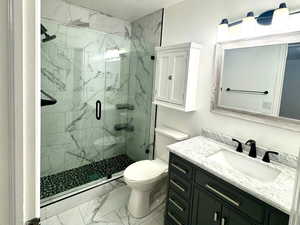 Master Bathroom featuring vanity, light marble finish flooring, a marble finish shower, and a textured ceiling