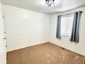 Carpeted empty room featuring baseboards and a textured ceiling