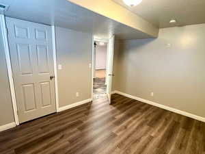 Finished basement featuring dark wood-type flooring and a textured ceiling