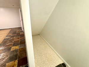 Under Stairs featuring baseboards and stone finish floors