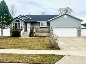 Single story home with driveway, stucco siding, an attached garage, and stone siding