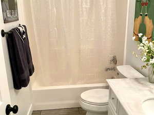 Bathroom featuring vanity, shower / tub combo, and finished floors