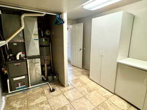 Below grade area featuring heating unit, a textured ceiling, and secured water heater