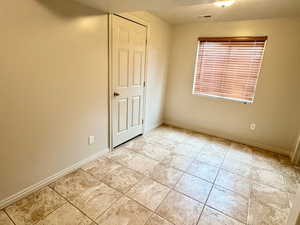 Unfurnished bedroom with baseboards and light tile patterned flooring