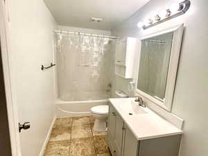 Full bath with vanity, shower / bathtub combination with curtain, and a textured ceiling