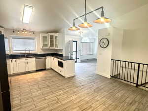 Kitchen featuring glass insert cabinets, dark countertops, white cabinets, finished floors, and freestanding refrigerator