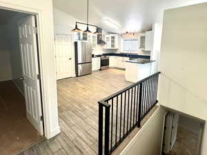 Kitchen featuring white cabinetry, dark countertops, stainless steel appliances, finished floors, and glass insert cabinets