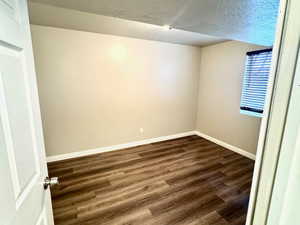 Unfurnished room with dark wood-style floors and a textured ceiling