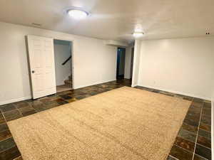 Finished basement with stone tile flooring and a textured ceiling