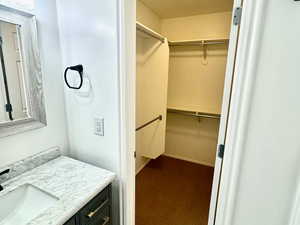 Bathroom featuring a walk in closet, vanity, and light marble finish floors