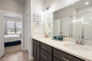 Bathroom featuring double vanity, a shower stall, ensuite bathroom, light tile patterned floors, and light colored carpet