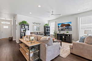 Living area featuring ceiling fan, dark wood finished floors, a chandelier, and a textured ceiling