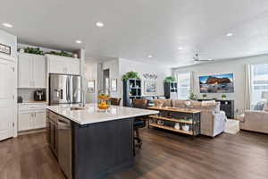 Kitchen featuring dual tone cabinetry, open floor plan, a kitchen breakfast bar, dark wood-style flooring, and plenty of natural light