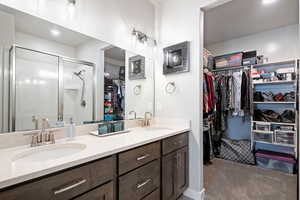 Full bathroom with a walk in closet, double vanity, light carpet, recessed lighting, and a stall shower