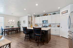 Kitchen featuring a center island with sink, tasteful backsplash, a breakfast bar, stainless steel appliances, and a textured ceiling