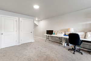 Home office with light colored carpet and recessed lighting