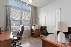 Office space with light carpet, ceiling fan, and a textured ceiling