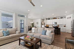 Living area with a ceiling fan, dark wood-type flooring, and hanging lights