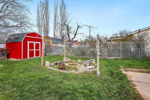 Fenced backyard featuring a shed, an outdoor fire pit, and a patio area