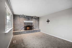Unfurnished living room featuring a fireplace and carpet flooring