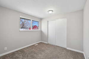 Unfurnished bedroom featuring a closet, carpet flooring, and a textured ceiling