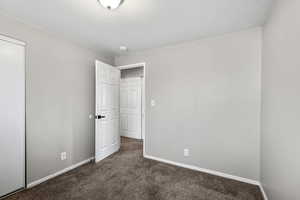 Unfurnished bedroom with dark carpet and a closet