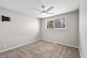 Spare room with carpet floors, ceiling fan, and a textured ceiling