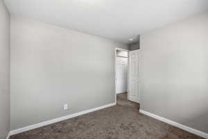 Spare room with dark carpet and a textured ceiling