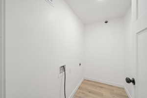 Laundry room featuring light wood-type flooring, hookup for a washing machine, and hookup for an electric dryer