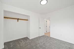 Unfurnished bedroom with carpet flooring and baseboards