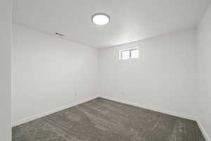 Spare room featuring dark colored carpet and a textured ceiling