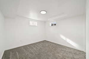 Basement with baseboards and dark colored carpet